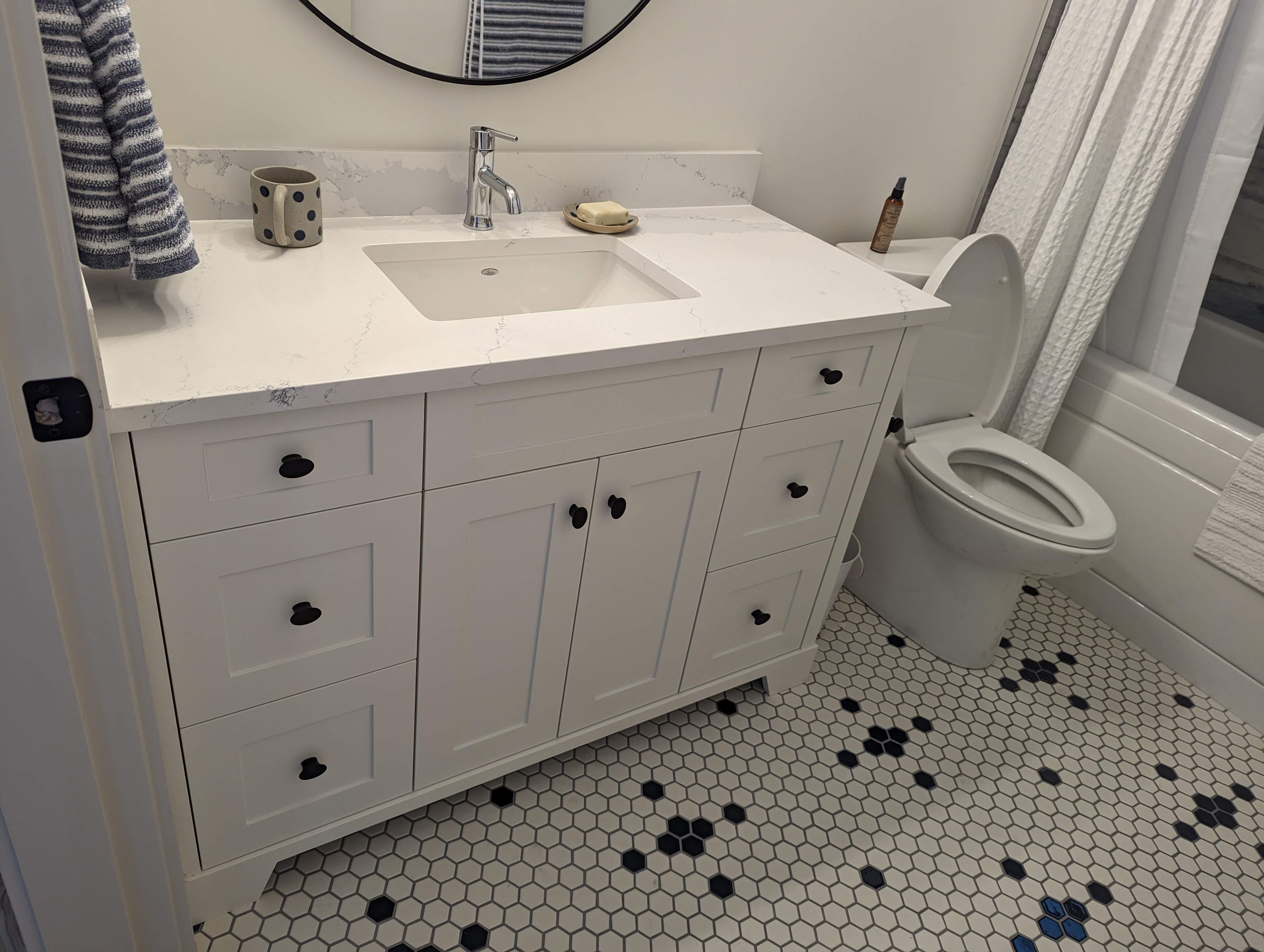 White painted bathroom vanity with black hardware and quartz top