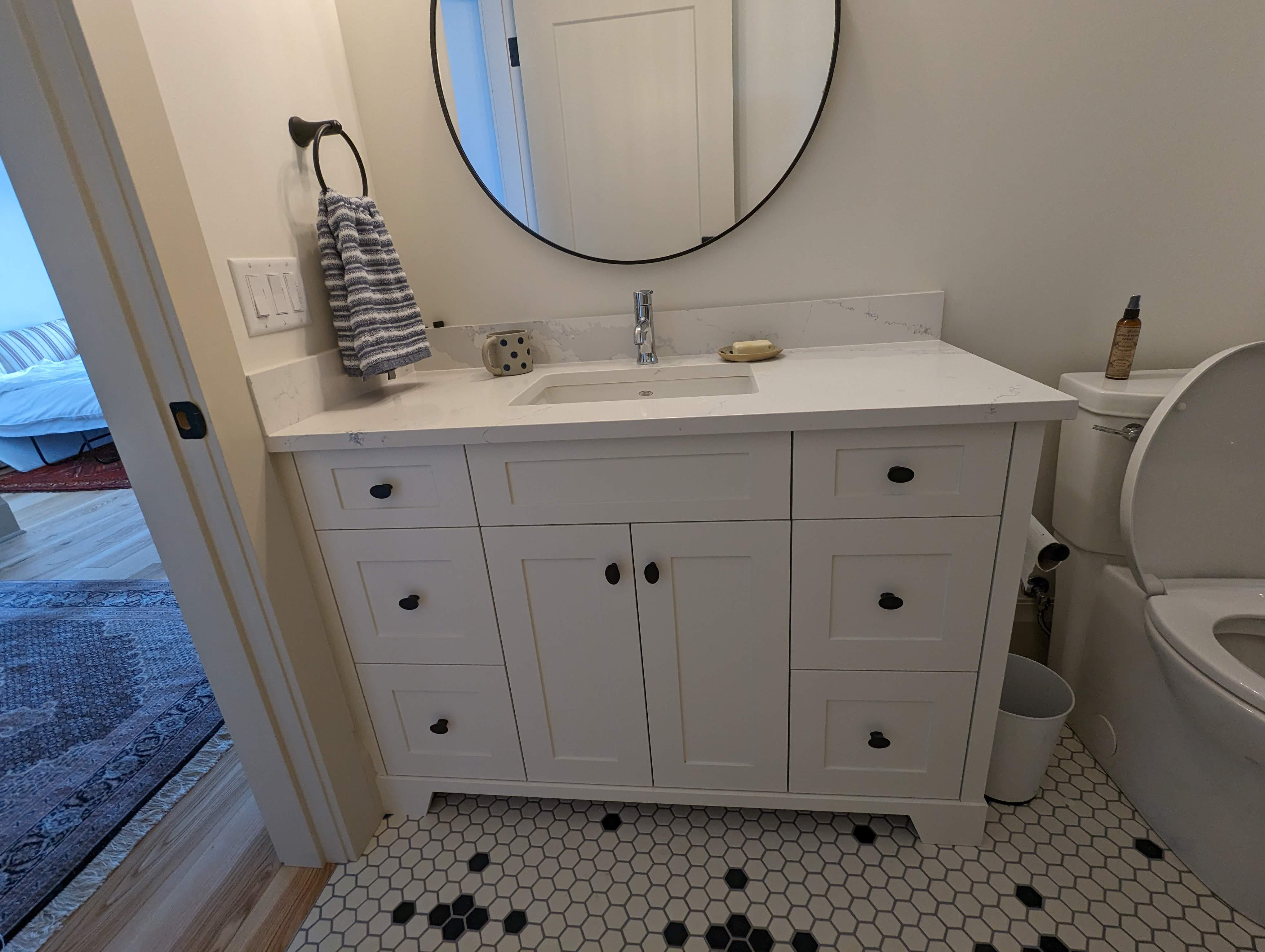 White painted bathroom vanity with black hardware and quartz top
