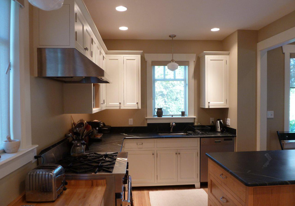 Frameless white kitchen with stainless range hood and maple island