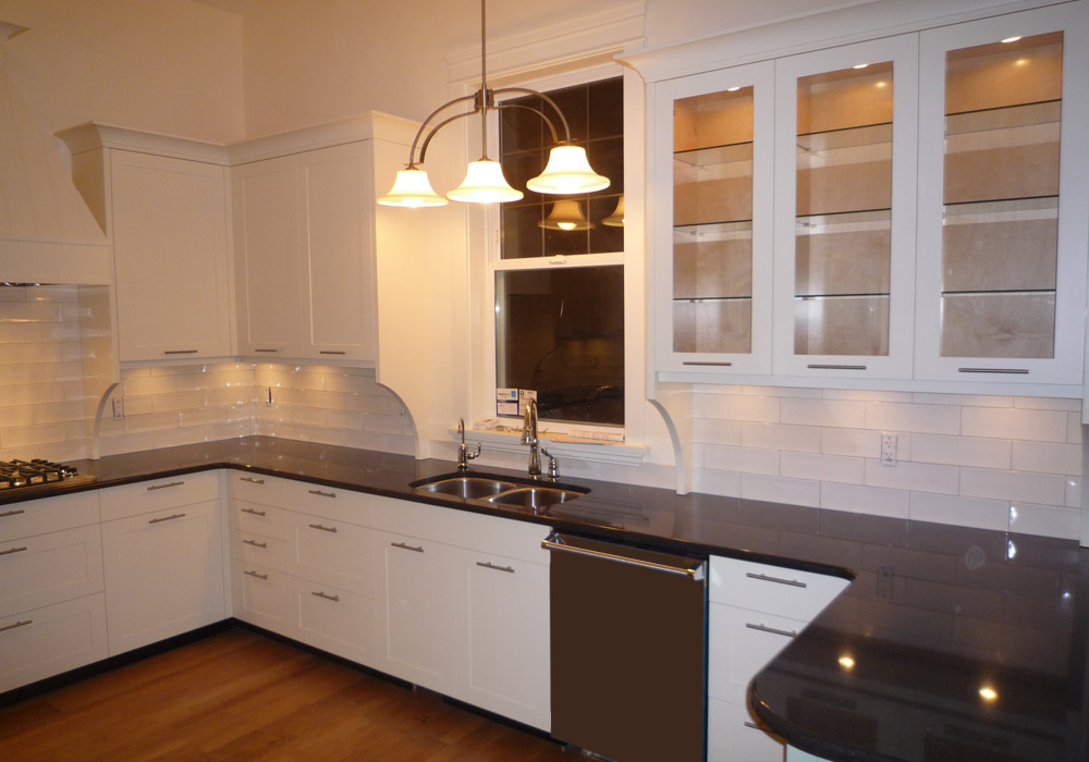White face-frame kitchen with glass upper cabinets and dark granite countertops