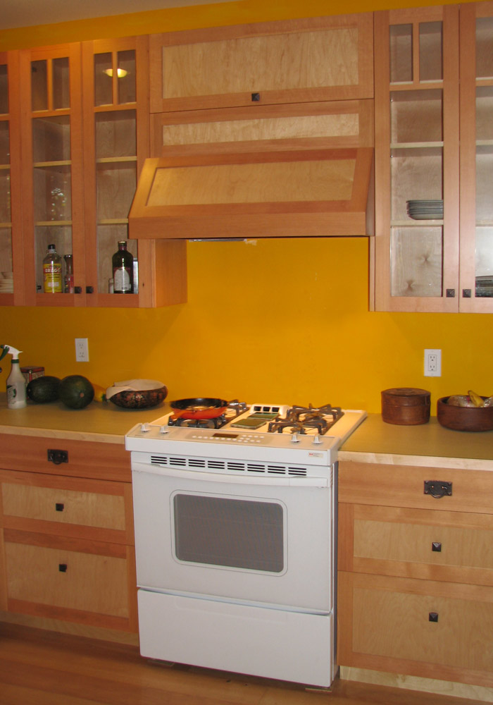 Frameless maple and birch kitchen with natural wood grain and custom painted hood