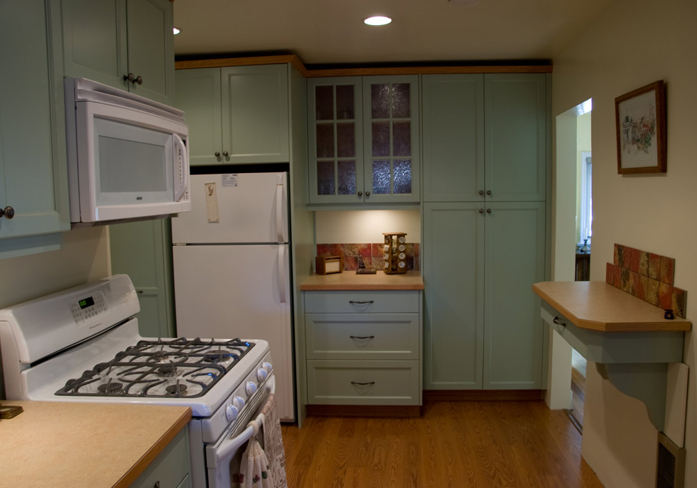 Sage green face-frame kitchen with floor-to-ceiling pantry and leaded glass upper cabinets